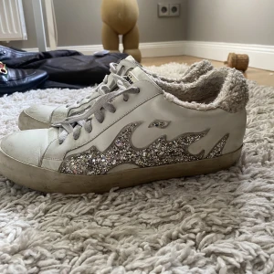 Sneakers - Golden Goose inspirerade sneakers som är vita med slitningar med silvrigt glitter och sen lurvigt på hälarna!! Verkligen så så coola😍😍😍 (De ska va slitna och ha ”fläckar” på sig, det är designen)