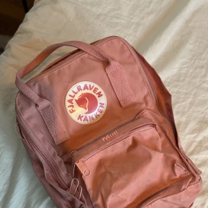 Fjällräven väska  - Fjällräven väska mini rosa, inte använd men dammig då den legat i en kartong i några år. Går att tvätta bort! Med justerbara band efter axelstorlek och längd