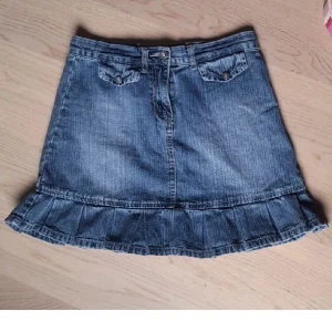 Jeanskjol - Minikjol av jeans med typ volang, snygga framfickor- mer bilder i gammal annons