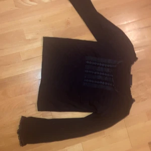 Svart topp med spets - Jättefin svart topp. På en längre kropp så sitter tröjan högt upp på magen och främjed kurvor. Fint spetsmönster fram och ärmar. 