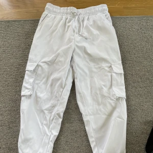 Cargo byxor - Vita cargo byxor med fickor på båda sidor av benen med spönnen som detaljer