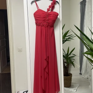 Bal/Fest klänning - blommig detalj - En jättefin bal/fest klänning i färgen fushia/rosa. Den har en fin blommig detalj på framsidan🌸😍priset kan diskuteras!