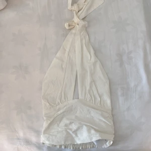 Halterneck topp - Halterneck topp från GinaTricot aldrig använd i storlek 36. Skulle även säga den passar en 38 då den är smockad i ryggen och stretchar ut sig. Den kan korsas men även knyta utan att korsa banden. Toppen är inte helt vit den är mer ljus cremevit.