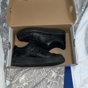 Air force 1s i svart - Skorna är i generellt bra skick men en av plastbitarna på skosnörets kant är av, det är lite crease men det syns inte så tydligt. Sitter bra på mig som är storlek 40