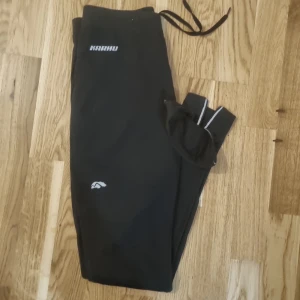 Träningstights med många funktioner.  - Träningstights från Karhu.  Dragkedja nedtill,knyt i midjan,ficka på baksidan, reflex detaljer. 