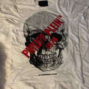  Philipp plein t-Shirt - Det är en vit Philipp plein t-shirt som är i storlek L. Tyget är lite tunt men man ser inte igenom tröjan. Säljer för att den inte kommer till användning och köpte den på Plick men den var för stor för mig som har M. Skriv gärna om ni vill ha fler bilder 