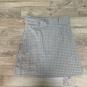 Rutig kjol - En kort och rutig beigefärgad kjol.