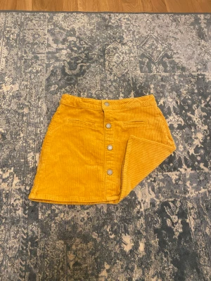 Gul kjol - En gul kjol som har fickor där fram silvriga knappar