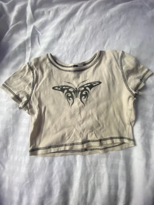Beige  topp  - En fin y2k topp med fjärlistryck på jag säljer eftersom den inte kommer till användning och är lite för liten 