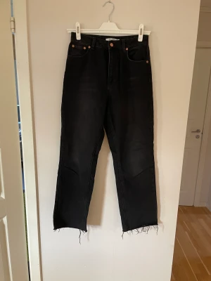 Jeans - Svartgråa jeans, avklippta nertill, slutar vid anklarna på mig som är 175 cm, högmidjade, använda ca 5 gånger. Säljer pga storlek ej passar