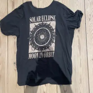 En svart t-shirt med ett astrologiskt tryck på