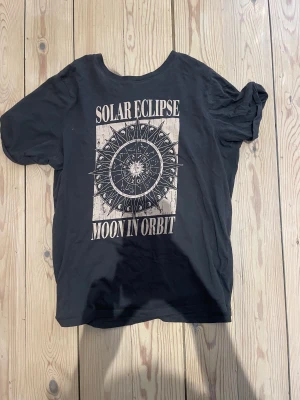Svart T-shirt med tryck  - En svart t-shirt med ett astrologiskt tryck på
