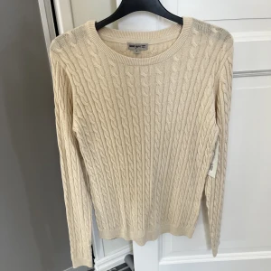 Kabelstickad tröja  - Beige kabelstickad tröja i storlek S. Aldrig använd, lappen sitter fortfarande kvar. 50kr plus frakt. Har mycket fler plagg ute tillsalu! 
