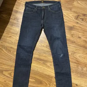 Mörkblåa Lee jeans. Storlek w31 l32 modellen LUKE. Byxorna är knappt använda men det finns ett litet hål på det ena benet annars är de så gott som nya. Hålet gör byxan lite tuffare enligt mig! Priset är därför även anpassat. 