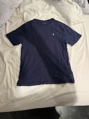 Polo Ralph Lauren T-shirt - Mörk blå Ralph Lauren t-shirt med vitt märke. Säljer för den har blivit för liten. Storlek M/S herr. Pris kan diskuteras vid snabb affär. 