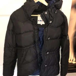 Mörkblå dunjacka pufferjacket  - Så snygg mörkblå dunjacka med dragsko i midjan. Påminner om Boomerang jackan. Strl 36. 