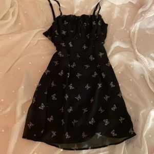 Svart klänning stl 38 - Suupersöt svart mesh klänning med vita fjärilar. Dragkedja på sidan och knytbar vid bröstet. 