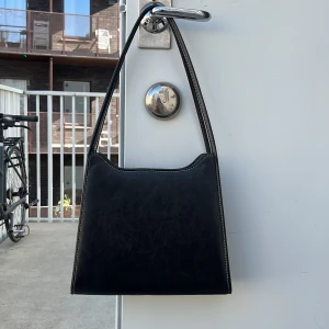 Svart väska  - Svart väska som stängs med dragkedja. Har ett innerfack för mobil och ett som stängs med dragkedja. Svårmåttad pga vinklarna, men djup typ 7cm, höjd typ 22 cm, bas typ 28.5 cm mått uppe typ 22.5. Fint använt skick 👜✨