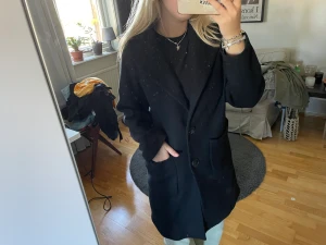 Svart kappa  - Superfin svart kappa i ullblandning från Zara. Sparsamt använd, tre knappar imitten och rymliga fickor 