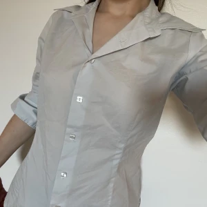 Skjorta  - Ljusblå skjorta med pärlemoknappar och trekvarts ärmar. Den är figursydd. Köpte den här men behövde den bara till ett bröllop så säljer vidare. En knapp saknas dock. 