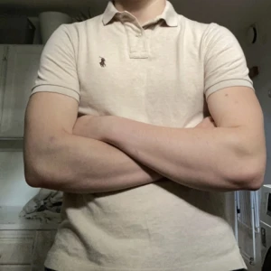 Ralph lauren pikétröja  - Beige pikétröja med brun logga ifrån Ralph lauren. Classic fit. Killen på bilden är 182cm och väger 77kg.