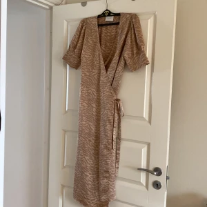 Neo noir omlottklänning - Neo noir beige/rosa omlottklänningen i nyskick. Använd två gånger. Köpt för 900 kr. 