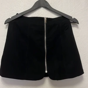 Kjom - Svart kjol i ”mocka”. Liten i storleken. Använd men i bra skick.