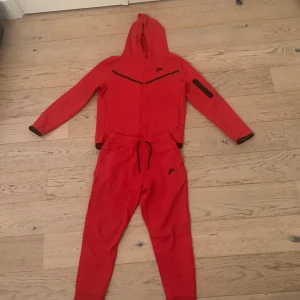 Nike tech fleece röd  - Nike tech fleece röd mycket bra skick och byxorna knappt använda och tröjan sparsamt använd. Storlekar är: Tröja: Junior XL (158-170 cm ) Byxor: Junior L (147-158 cm )