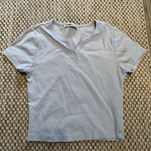T-shirt  - En söt ljusblå t-shirt, lite kortare och med ett litet snygg mellan brösten. Super skön en varm sommardag!💕