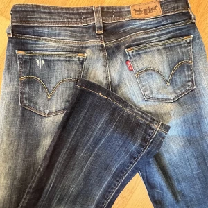 Lågmidjade utsvängda jeans Levis - Ett par låga bootcut jeans från Levis. Midjemått tvärs över 35 cm. Innerbenslängd 77 cm. Passar perfekt på mig med storlek S. Modell 572 bootcut. Verkligen en av mina favoriter men säljer på grund av att jag har flera liknande par!❤️