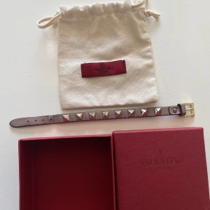 Valentino Garavani Rockstud Bracelet - Hej, säljer ett Valentino armband i en snygg rosa/grå färg. Bra skick, alla nitar kvar osv. Finns en  liten flaw, DM för info. Nypris 2945kr. Box samt påse medkommer vid köp. Unisex, passar både herr och dam. Priset är inte hugget i sten. Hör av dig!