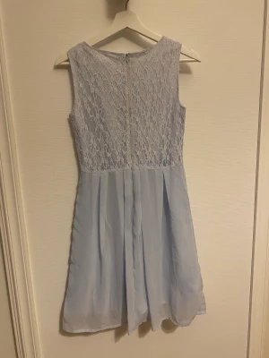 Blå klänning  - Super fin klänning med blommig textur i brodyr. Klänningen är k storlek 164 och är från Emoi.