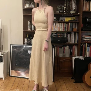 Beige midiklänning med knytning i ryggen - Beige midiklänning. Tre par band att knyta baktill.   Aldrig använd!