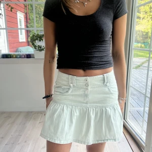 Minikjol - Supersöt minikjol i fin ljusgrön färg. Jeansmaterial med volanger. Fint skick!