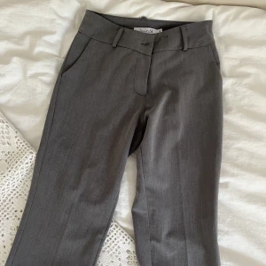 Gråa lågmidjade kostymbyxor - 💜Lägger upp plagget igen pga oseriös köpare💜As snygga kostymbyxor från design by si🌸🌸🌸 Är i storlek XS men sitter som xss, passar mig ej längre därav ingen passforms bild💞  (Andra bilden är lånad) Midjemått, 64 cm. Innerbenslängd, 82 cm. De är lågmidjade🪻