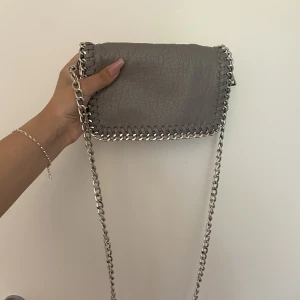 TIAMO väska grå - ANVÄND GÄRNA KÖP NU❤️Nyskick! En väska från Tiamo. Man kan ha kedjan lång men även göra den till en Axelväska/baguettväska (Se bilder, har ”vikt” kedjan på mitten)