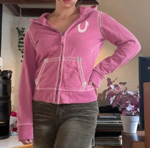 True religion hoodie - Så fin rosa true religion hoodie💕 den är barnstorlek så ganska kort i ärmen, uppskattar till xs i dam!! Lånade bilder, säljer då den tyvärr inte passade (finns  fortfarande)