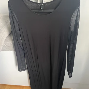 Lång svart klänning med genomskinliga armar - En fin långklänning från h&m i storlek medium som har genomskinliga armar