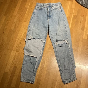 Jeans  - Loos mom jeans med hög midja och Ankelkorta  Ena benet har hålet revats upp lite mer