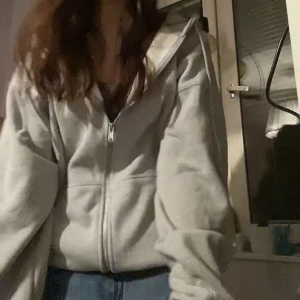 Grå oversized zipup - Super mysig zip hoodie från Brandy Melville. Knappt använd för den inte satt så fint på mig tvättat en gång. Perfekt till hösten/vintern. Jag är 160 och den är väldigt oversized på mig, Obs! På första bilden är den uppvikt, skriv för fler bilder/mått☺️🪻