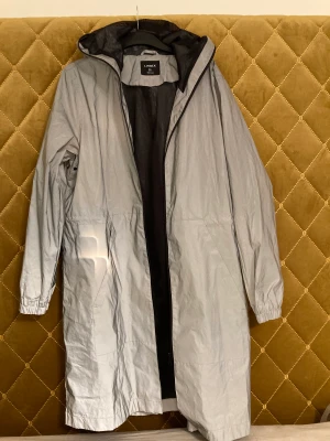 Regnkappa, Lindex - Regnkappa från Lindex. Polyester, reflex tyg. Strl L, använd endast en gång. Jag är 165cm lång, den går lite över knäna på mig. Köparen står för frakt  