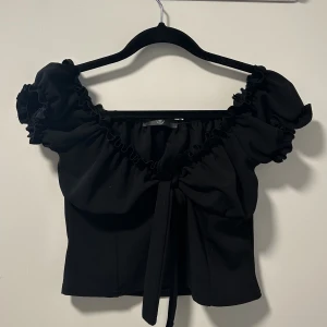 Topp - Svart offshoulder topp som aldrig använts. Knytning i mitten i storlek M