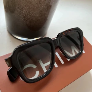 Chili solglasögon  - Säljer mina Chimi solglasögon, köp här på Plick men var lite stora på mig annars väldigt snygga och i bra skick! Box & fodral ingår, glaset är mörkat med en ton av grönt och ramen är brun/svart flammigt.  