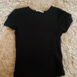 Ribbad basic t-shirt - Säljer en svart basic ribbad t-shirt från kappahl i storlek 158/164. Har en sjukt snygg passform. Passar perfekt till sommaren.