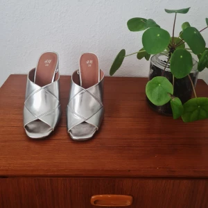 Klackskor silver  - Säljer mina skor som köptes på HMs hemsida för några år sedan. Använde de en gång men de är försmå så sedan dess har de bara stått som prydnad. Hoppas på att de kan få komma till användning för ngn annan. Klackhöjd, 11 cm 👠