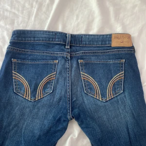 Utsvängda Lågmidjade mörkblå hollister jeans - Lågmidjade utsvängda hollister jeans. Tror dessa inte går att köpa längre på deras hemsida. Dom är ansvända men de är inga märken på dom eller något sånt så dom är i bra skick. Storleken är W26 och L33, dom är långa och rätt längd för mig som är 162.