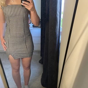 Rutig klänning med slits  - Klänningen är rutig med breda axelband och en liten slits. Sitter ganska tajt och framhäver kroppens former väldigt fint.  60 kr + frakt.  