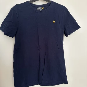 Lyle & Scott T-shirt - En mmörkblå Lyle & Scott T-shirt som är köpt på kidsbrandstore. Storlek 14-15år (Längd 164-170cm. Byst 86-88cm. Midja 75-76cm) (Kidsbrandstores storleksguide) Färg: Navy Blazer