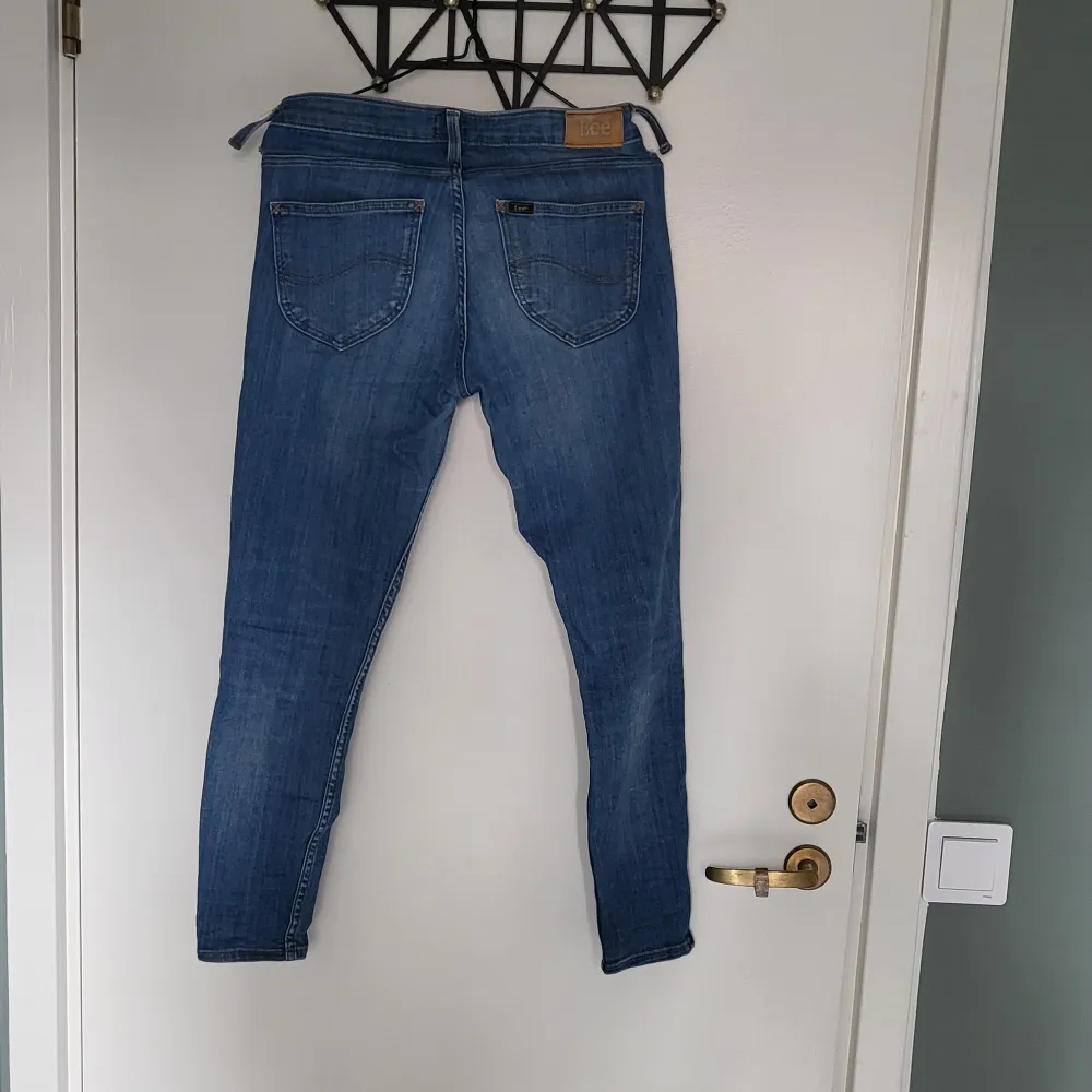 Blå jeans från Lee modell Scarlett cropped, W27/L31. Dekorativ dragkedja i benslut, 2 st hällor lösa se bild, ankellånga. Jeans & Byxor.