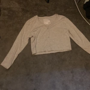 Långärmad  - Grå långärmad tröja med knappar fram.Fint skick helt nya och aldrig använt 